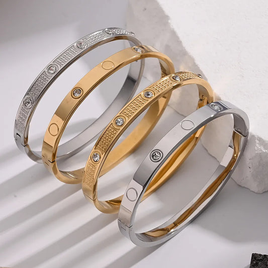 Gold and silver bangles with cubic zirconia crystals displayed on a plain background.