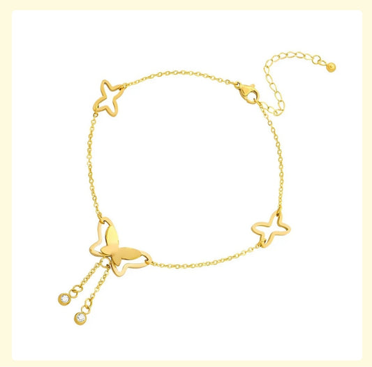 Gold anklet with butterfly and star designs on a light yellow background