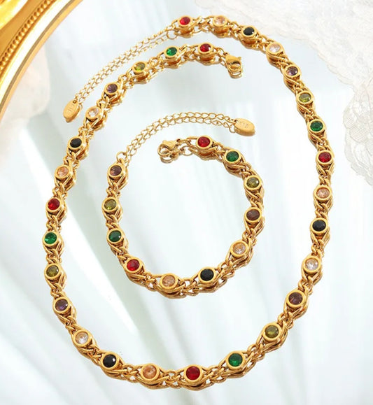 Gold necklace and bracelet with colored stones on a white background