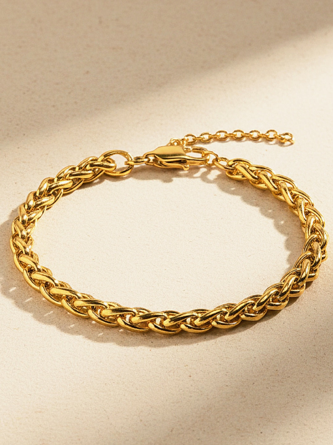 Gold chain bracelet on a beige background