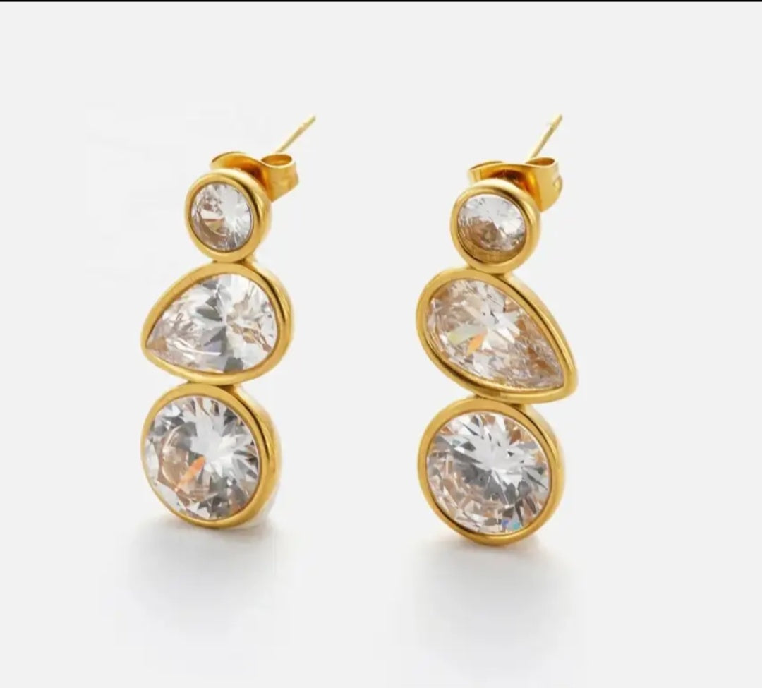 Gold earrings with clear gemstones on a white background