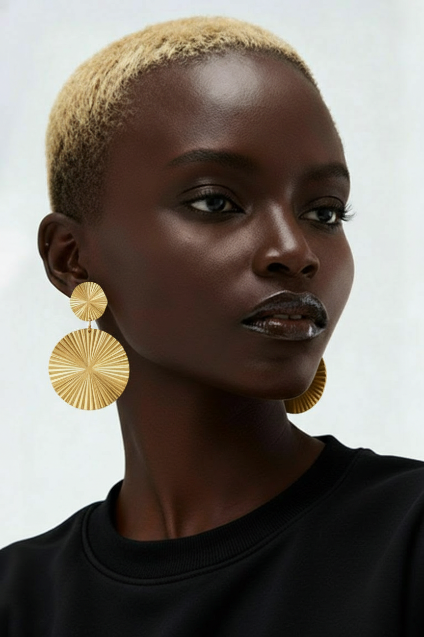 Woman wearing gold earrings against a neutral background