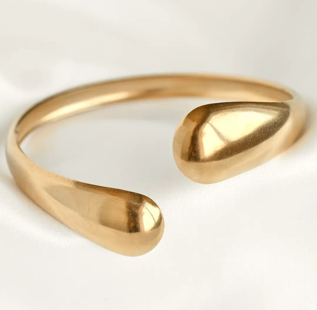 Gold open wrap around  bracelet on a light gray background