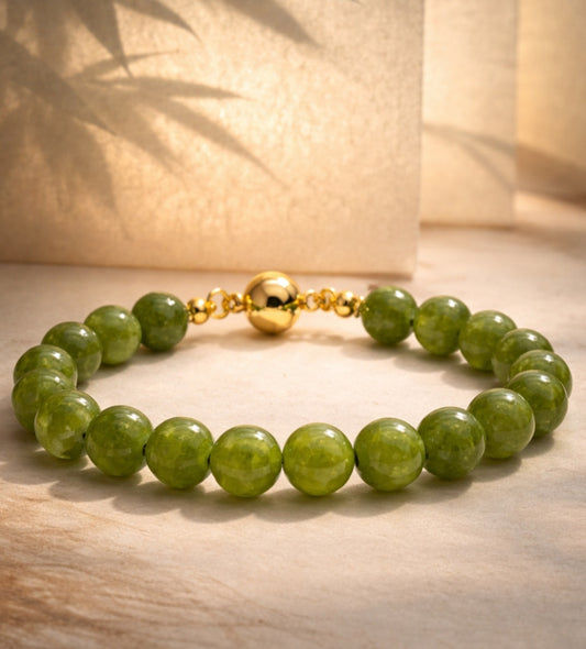 Green Agate beaded bracelet with a gold clasp on a wooden surface