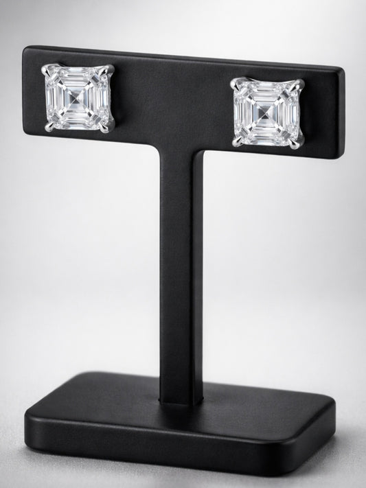 Pair of diamond earrings on a black T-shaped stand against a white background.