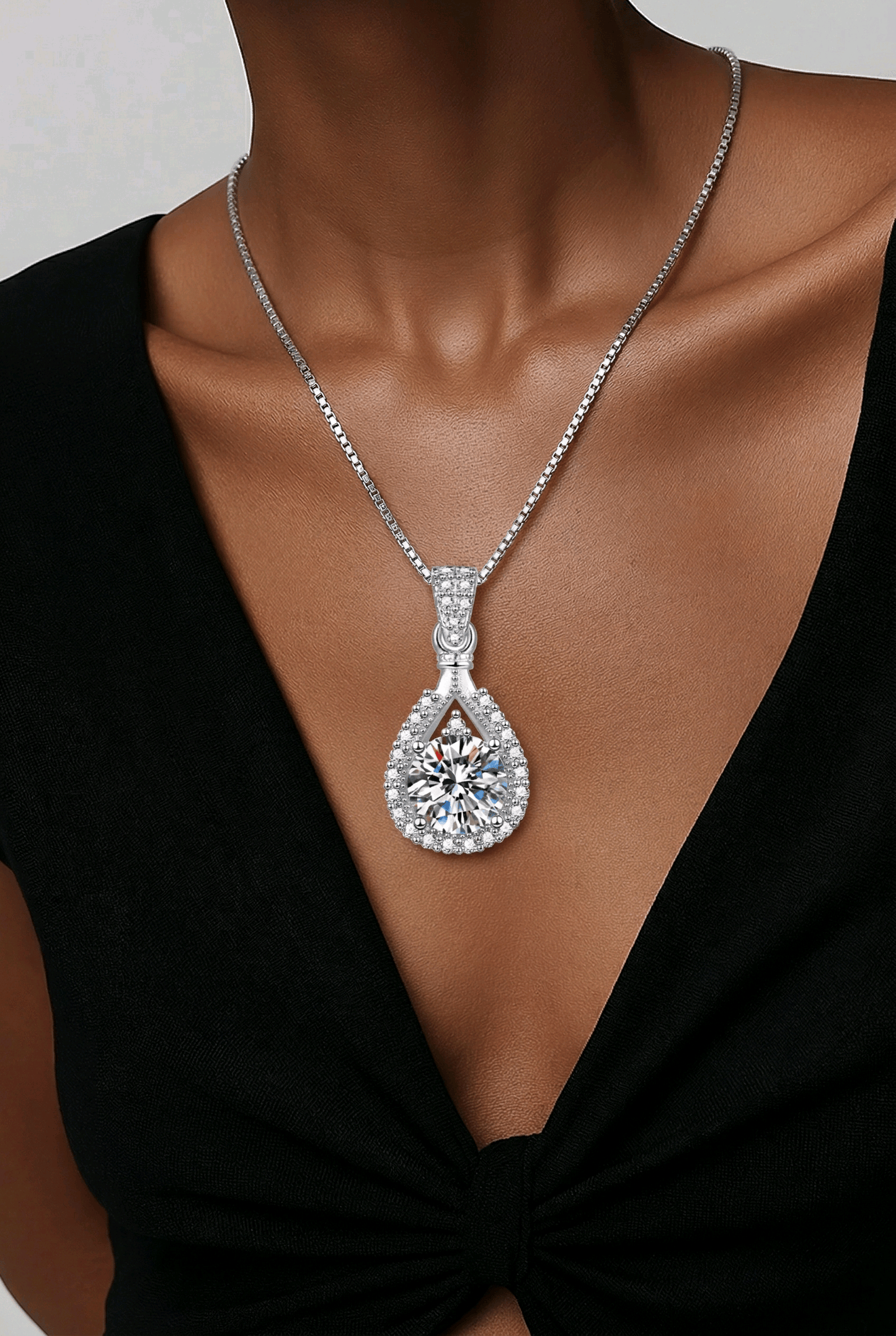 Teardrop-shaped Moissanite pendant necklace on a person wearing a black dress.