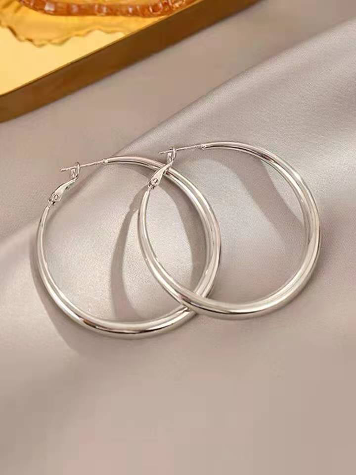 Large silver hoop earrings on a light fabric background